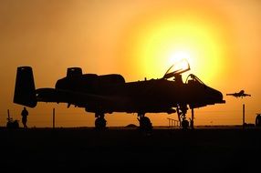 silhouette of military aircraft on ground at sunset sky