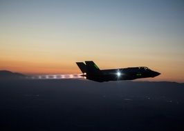 military fighter jet in the evening sky