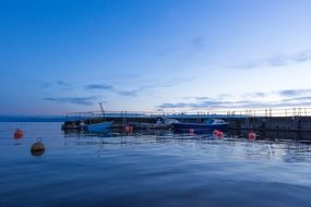 blue hour, boats and buoys at pier on calm water