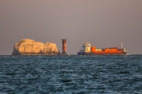 lighthouse and cargo ship in the ocean