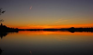 orange sunset on the horizon over the lake with the reflection