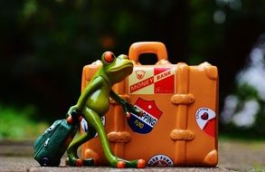Toy frog with a suitcase on holiday