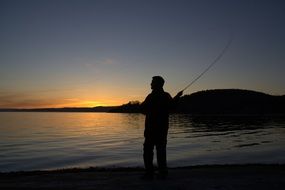 Silhouette of the person Fishing at colorful sunset background in Norway