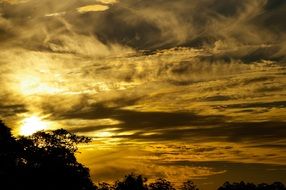 yellow sunlight behind the clouds at dusk