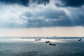 sun rays through the clouds over boats on the ocean