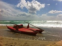 two red rowing boats on beach at sea
