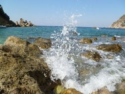 splashes of the sea on the stony shore of Corfu