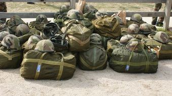 military load, travel bags and helmets on sand