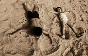 children playing angels on the beach