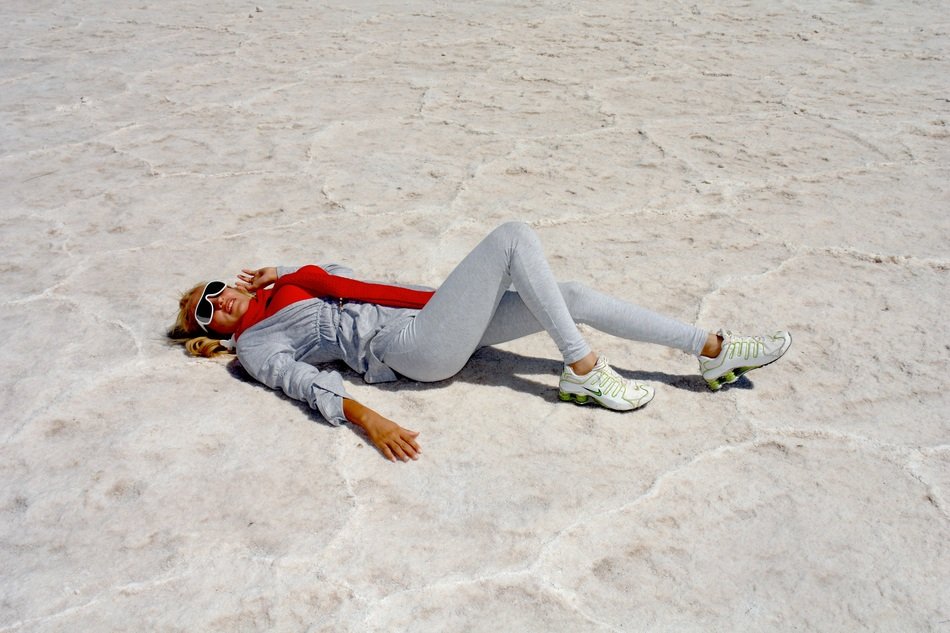 a girl lies on white sand on the coast