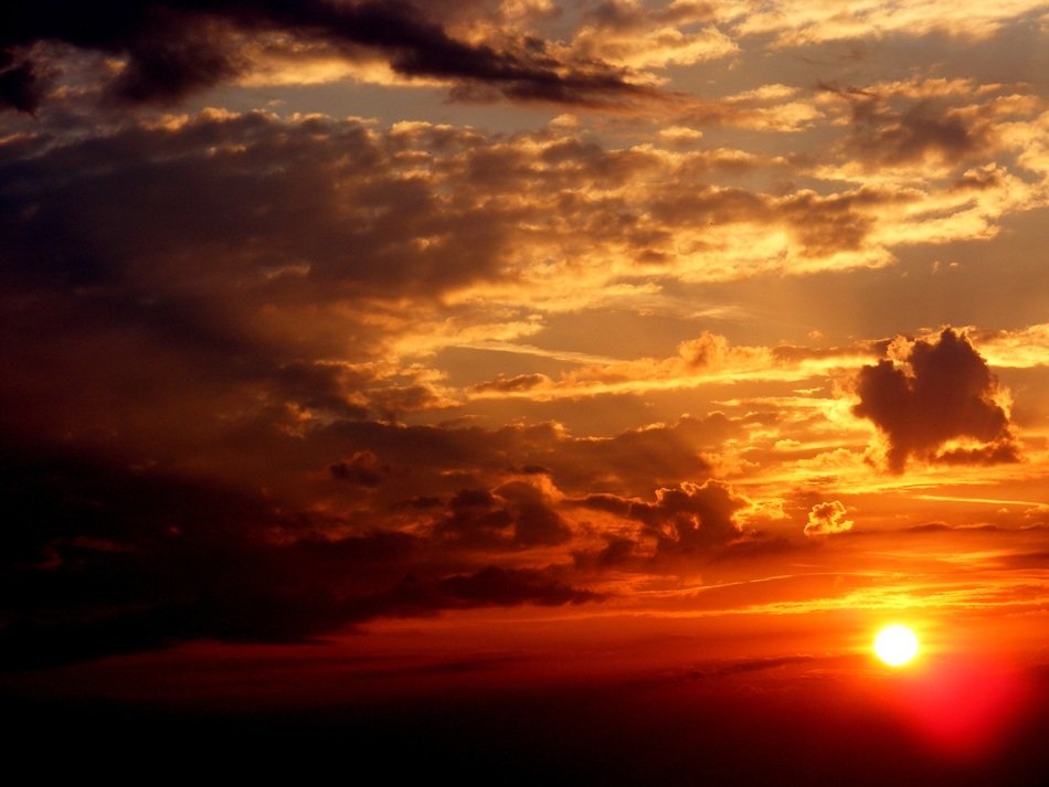 View in the distance sun at sunset amid the clouds