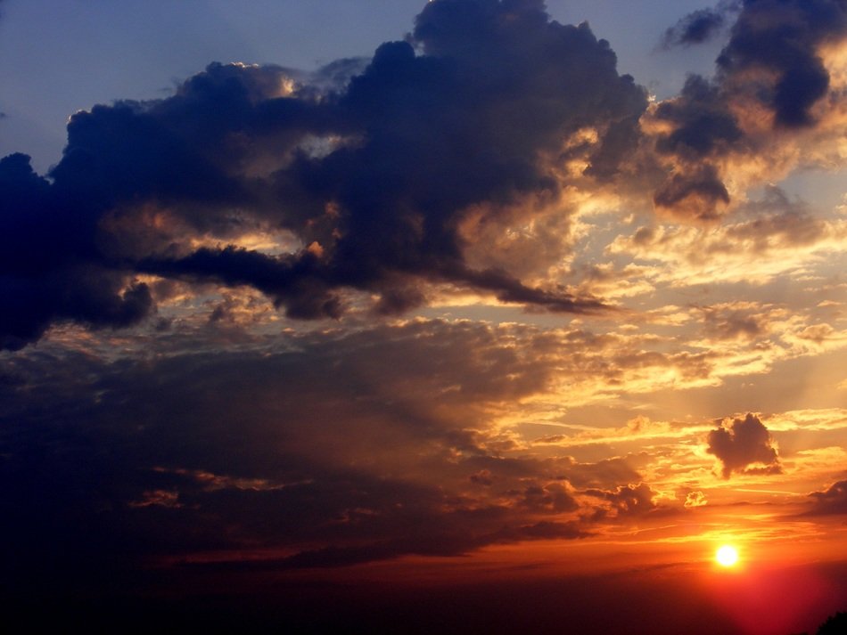 Huge clouds against the sun at sunset