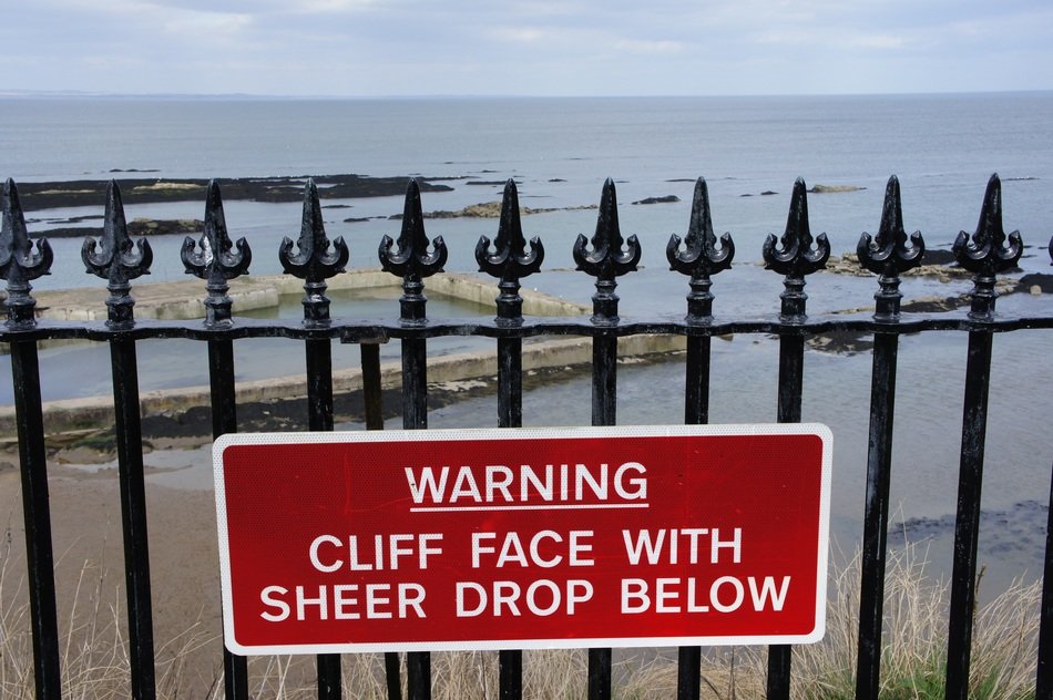 warning sign cliff face with syeer drop below