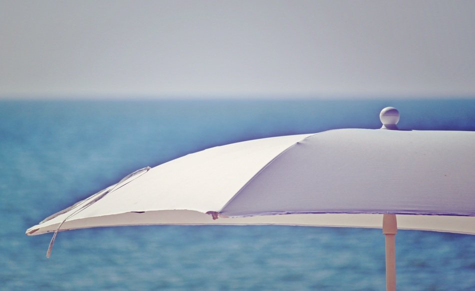 part of white parasol on blurred blue water background