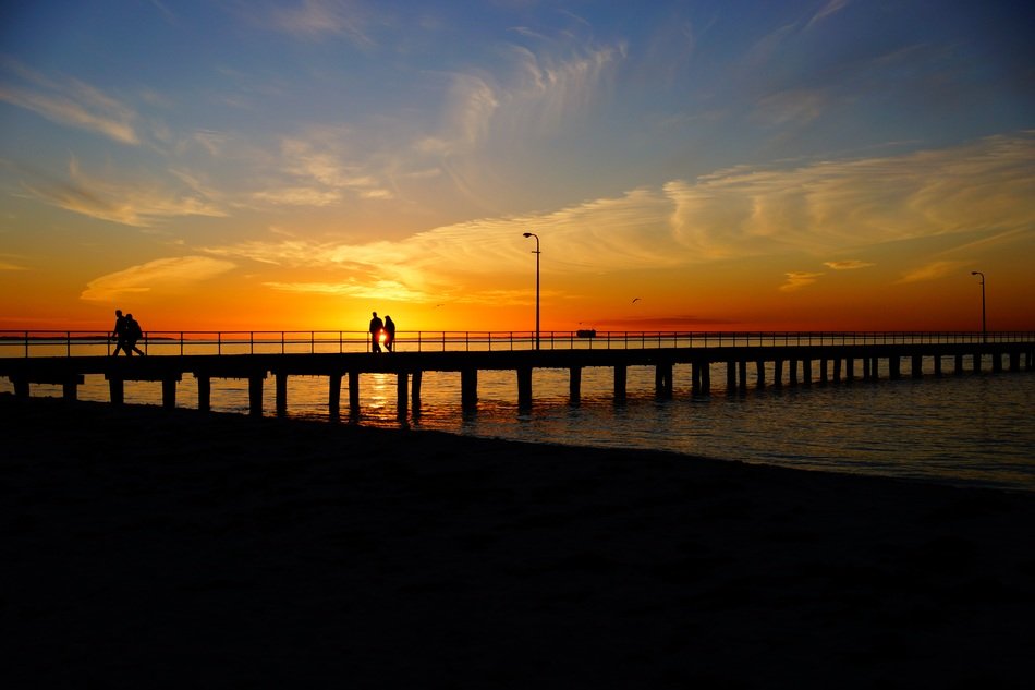 people on jetty pier sunset panorama