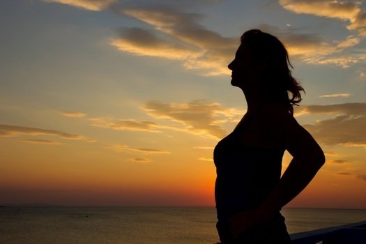 silhouette of the woman in the sunset rays