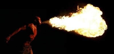 man blowing fire from mouth in darkness