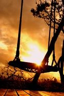 silhouette of a swing on a background of golden sunset