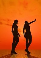 Silhouettes of women on the orange sunset