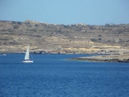 sailboat along the rocky coast of the mediterranean sea