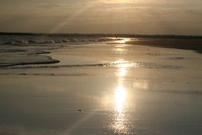 shiny beach surf in light at colorful sunset