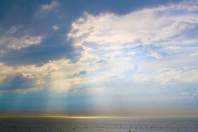 sun rays bursting through clouds above sea at morning