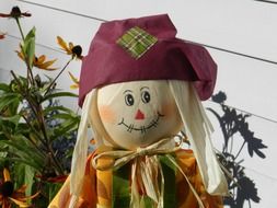 cute scarecrow on flower bed at autumn