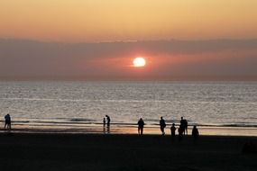 people on the lake on the background of pink sunset