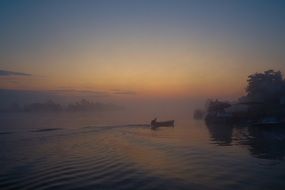 boats on a lake in the fog at sunset