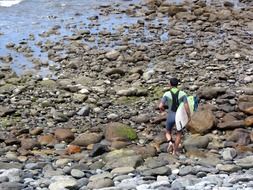 surfer walking in stone beach