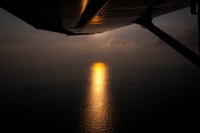 wing of the plane on the background of the trail of the setting sun on the ocean