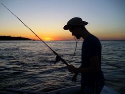 fisherman in a hat at sunset