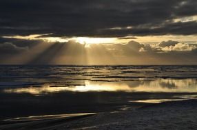 sunbeams through dark clouds in sunset seascape