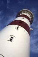 bottom view of striped lighthouse on the sea coast