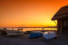 glow of a orange sunset over boats on the shore