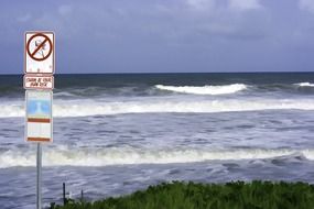 warning signs on the shoreline of ocean