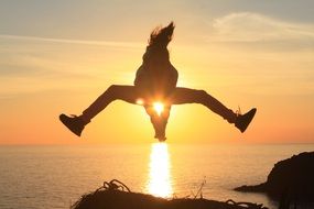 silhouette of young girl in jump at sunset sky