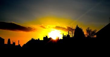 bright yellow blinding evening sun behind the city silhouettes