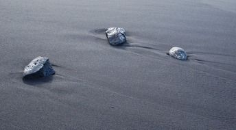 three stones on the sand on the coast