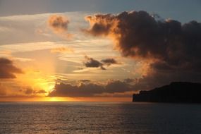 dark clouds and golden sun over the sea