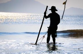silhouette of a fisherman on the shore of a reservoir at sunrise