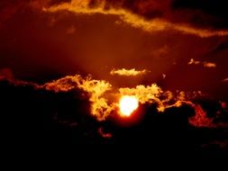 The fiery sun at sunset amid the clouds
