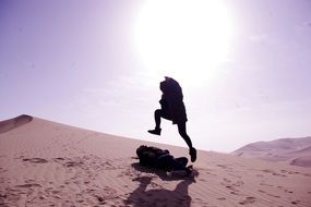 tourist jumping over the sand dunes in Dunhuang