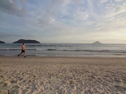 man runs along the sandy beach