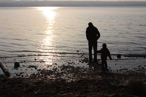 father and son on the lake at sunset