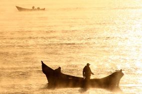 fishermen on boats in the morning haze at sunrise