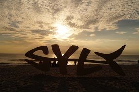 sylt, fish form modern art object silhouette on sunset beach, germany