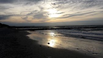 cirrus clouds at sunset above sea and dark beach