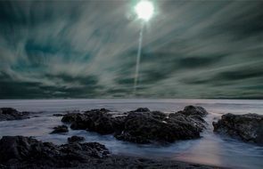 Bright colorful misty night sky over rocky beach