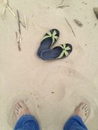 photo of feet and sandals on sand